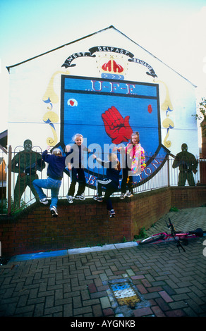 Les enfants de la rue jouant murales loyalistes .sur les rues de Shankhill Road illustrant les luttes paramilitaires, l'Ouest de Belfast Banque D'Images