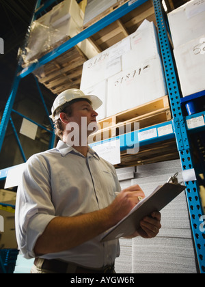 Warehouse worker writing on clipboard Banque D'Images