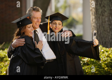 Père et filles diplômés taking own photograph Banque D'Images