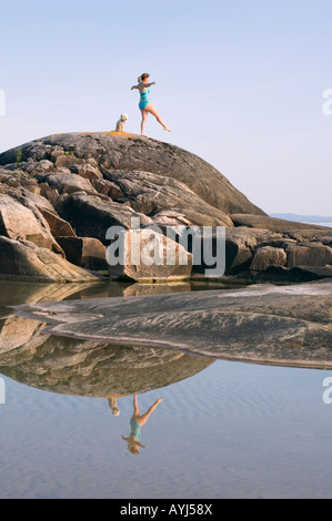 Femme ET CHIEN SUR ROCK LE LONG DES RIVES DU LAC SUPÉRIEUR DANS LE NORD DE L'ONTARIO Banque D'Images