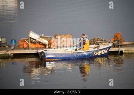 Le NORD DU PAYS DE GALLES CONWY UK Octobre deux hommes dans une petite embarcation à moteur de déchargement sont une prise de moules sur une plate-forme sur la rivière Conwy Banque D'Images