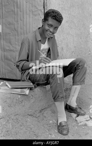 Portrait en noir et blanc d'un jeune tigrayan heureux, en train de rire et en herbe qui étudie à sa porte.Mekelle, Tigray, Éthiopie, Afrique Banque D'Images