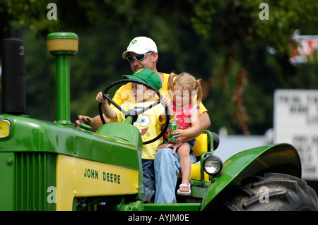 Père avec de jeunes fils et sa fille sur un tracteur John Deere Banque D'Images