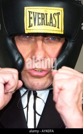 En homme d'une quarantaine d'wearing head protector protège-dents et soulève ses poings près de son visage trouver une pose de boxe Banque D'Images