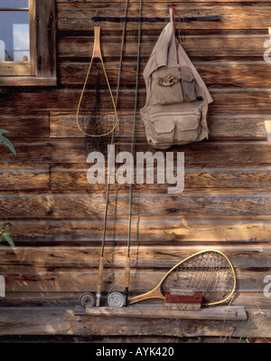 Les cannes de pêche à la mouche filets et boîtes de voler la veste de pêche et pendaison le mur extérieur du chalet de pêche Montana USA Banque D'Images