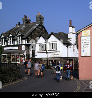 Hawkshead Lake District village dog walking & quelques touristes sac à dos à côté de Beatrix Potter cadeaux inscription personnes dans rue étroite Cumbria England UK Banque D'Images