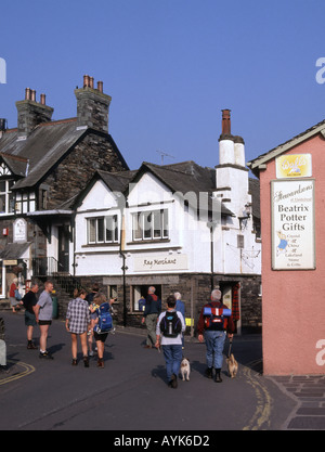 Hawkshead Lake District village dog walking & quelques touristes sac à dos à côté de Beatrix Potter cadeaux inscription personnes dans rue étroite Cumbria England UK Banque D'Images