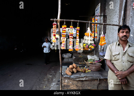 Inde MUMBAI Vendeur vente de guirlandes de fleurs et les noix de coco que les hindous utilisent comme offrandes dans leur culte de la dieux hindous Banque D'Images