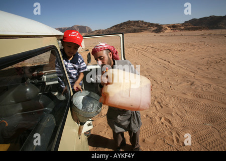 Un chauffeur de Digitals son réservoir d'essence dans le désert.Les visiteurs peuvent tour le Wadi Rum en voiture. Banque D'Images