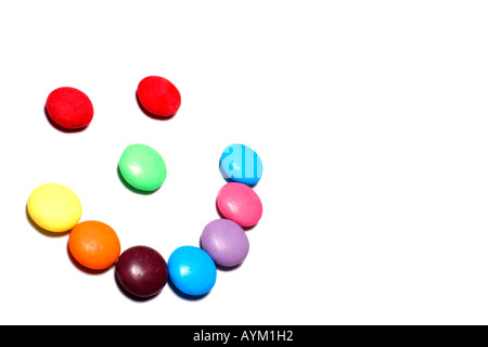 Bonbons colorés disposés dans un smiley sur un fond blanc avec copie espace Banque D'Images