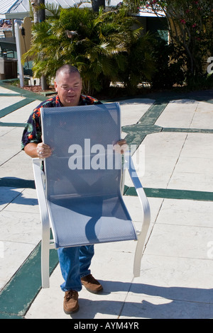 Homme d'âge moyen portant un fauteuil Piscine Banque D'Images