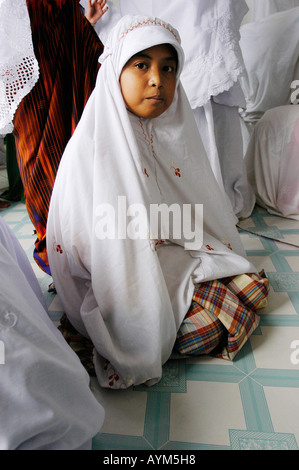 Un jeune orphelin jeune musulmane à Aceh en Indonésie au cours de sa prière. Banque D'Images
