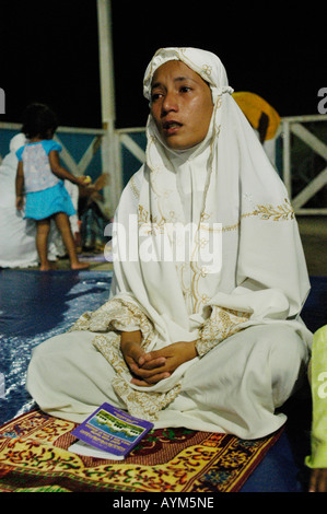 Une jeune musulmane à Banda Aceh en Indonésie est prier dans la nuit précédant le 1 anniversaire du tsunami de 2004. Banque D'Images