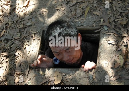 Un visiteur de la Cu Chi Tunnels à Ben Duoc a du mal à quitter le piège étroit tunnel porte donnant dans le système. Banque D'Images