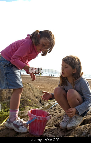 Les jeunes filles âgées de six à la pêche par des rochers au bord de la mer. Devon Woolacombe. Banque D'Images