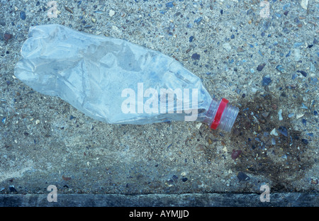 Close up of a mis fin à la bouteille en plastique transparent avec bouchon rouge, l'anneau allongé sur le béton avec tache humide à la bouche Banque D'Images