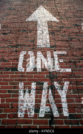 One way sign peint sur un vieux brick lane pointant vers le haut. Banque D'Images