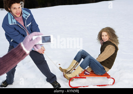 Personne de prendre une photo d'un couple hétérosexuel dans la neige avec un téléphone mobile, selective focus Banque D'Images