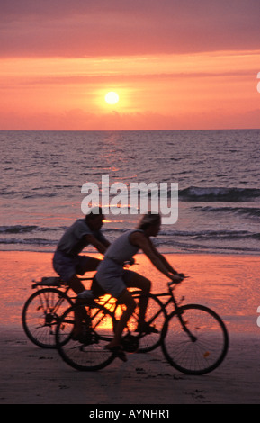 Sud de Goa, Inde. Un couple à vélo découpé sur le coucher de soleil sur plage de Colva à Benaulim. Janvier 2006. Banque D'Images