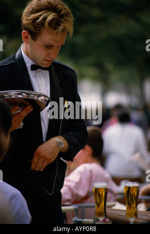 FRANCE Ile de France Paris Serveur dans black tie holding tray et de rendu aux clients pour leurs verres de bière sur la table Banque D'Images