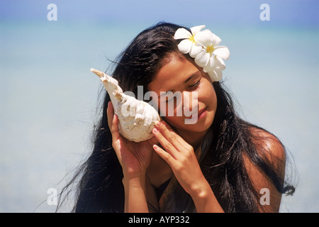 Les jeunes des Îles Cook holding seashell à son oreille Banque D'Images