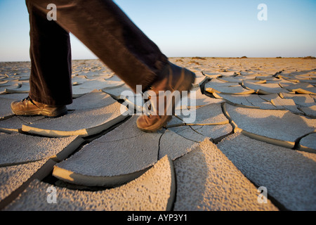 Personne avec des bottes de randonnée marche sur la boue sèche fissuré dans le désert du Namib Banque D'Images