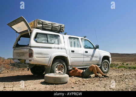 Le changement d'un pneu à plat sur un véhicule hors route (4X4) dans le nord de la Namibie, l'Afrique Banque D'Images