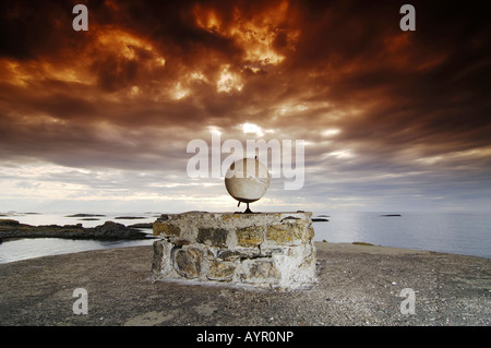 Pas de sculpture, rouge dramatique ciel nuageux, globe en béton sur un socle en pierre, dans le nord de la Norvège, Scandinavie Banque D'Images