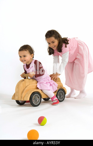 Deux petites filles, sœurs, jouant avec des boules en bois et voiture Banque D'Images