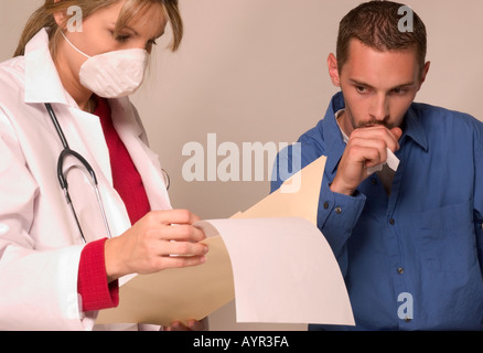 Homme patient tousse alors que les GP rapport lit Banque D'Images