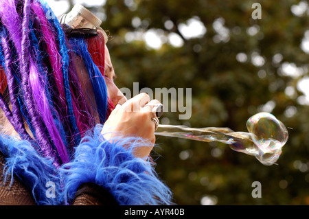 Goths pendant le Festival de musique Castle Party à Bolkow en Pologne. Personne avec des dreadlocks bleus et violets soufflant une bulle à un événement gothique. Banque D'Images