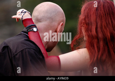 Goths au Castle Party Music Festival à Bolkow, Pologne. Une femme aux cheveux roux et à la manche en filet embrasse un homme chauve par derrière. Banque D'Images