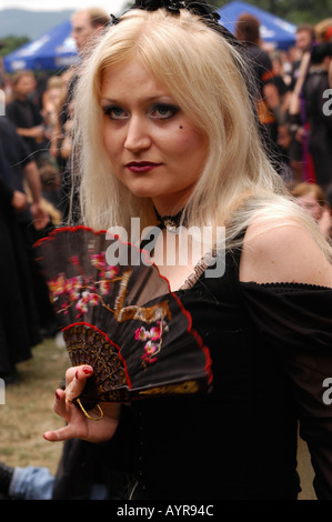 Goths pendant le Festival de musique Castle Party à Bolkow en Pologne. Une femme blonde en tenue gothique avec un ventilateur décoratif à l'événement en plein air. Banque D'Images