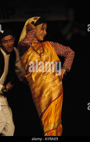 Homme et femme népalais en robe traditionnelle colorée exécutent des danses nationales sur scène. Spectacle culturel dynamique mettant en valeur le patrimoine du Népal. Banque D'Images