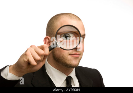 Young man holding magnifying glass en face de son visage Banque D'Images