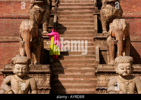 Jeune fille posant sur les étapes entre les deux statues dans le temple de Nyatapola, Taumadhi Square, Bhaktapur, Népal, Asie Banque D'Images