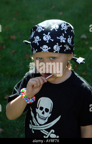 Fille avec des symboles de pirate crâne et épées croisées sur sa chemise en lui léchant le lolly Banque D'Images