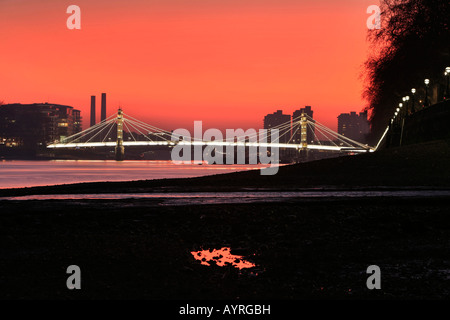 Albert Bridge peu après le coucher du soleil, le feu-rouge ciel vu à partir de la banque de la Thames, Chelsea Embankment, London, England, UK Banque D'Images