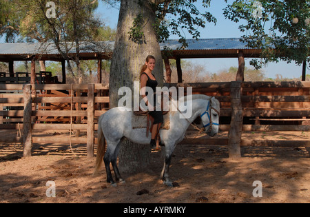 Jeune femme sur un cheval blanc à un corral sur une ferme, Gran Chaco paraguayen, Paraguay, Amérique du Sud Banque D'Images