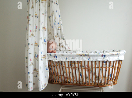 Bébé de quatre mois garçon lorgnant sur le bord de son berceau Banque D'Images