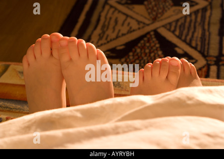 Des profils de femme et de pieds de l'enfant, à l'sous une couverture Banque D'Images