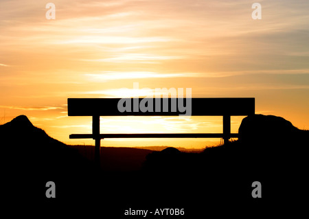 Banc de parc vide découpé sur le coucher du soleil Banque D'Images