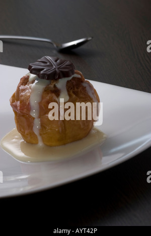 Pomme au four rempli de massepain, saupoudrées de cannelle et couvert de sauce à la vanille sur une plaque Banque D'Images
