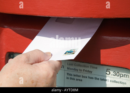 England UK Close-up of person's hand holding lettre avec cachet 2e classe d'afficher en rouge postbox Banque D'Images