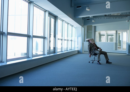 Épuisé businessman sitting in un bureau vide Banque D'Images