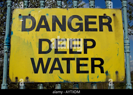 Danger l'eau profonde, un panneau d'avertissement avec un texte noir sur un fond jaune par la Tamise, à Kingston, Surrey, Angleterre Banque D'Images