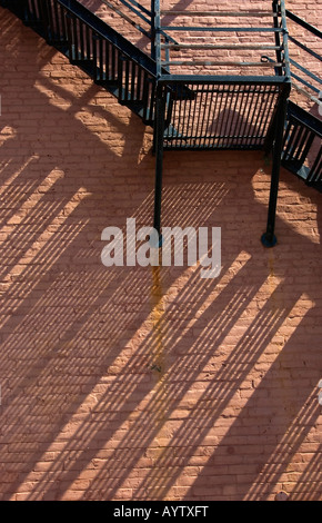Escalier de secours en métal avec des ombres obliques sur mur de brique Banque D'Images