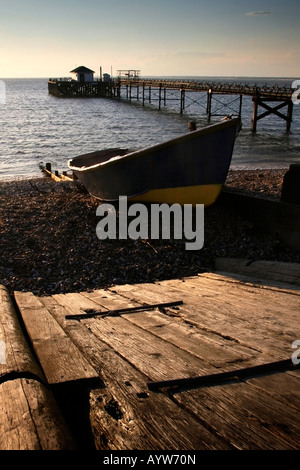 Canot sur la plage au coucher du soleil à côté de la jetée, Totland Bay Île de Wight Banque D'Images