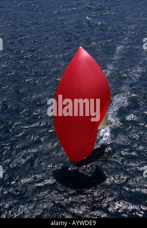 Spinnaker rouge vif de voilier bateau approchant pas visible à partir de la lueur du soleil Vue aérienne des ondes FRANCE Banque D'Images