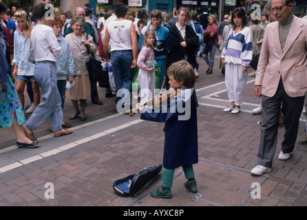 Un petit garçon joue son violon musicien ambulant dans Grafton Street, Dublin Street vu par une foule d'admirateurs Banque D'Images